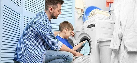 L’image montre un père et son fils en train de charger le lave-linge.