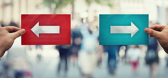 Photo de deux mains tenant des flèches qui pointent dans des directions opposées.