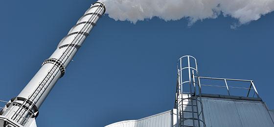 The picture shows a smoking factory chimney.