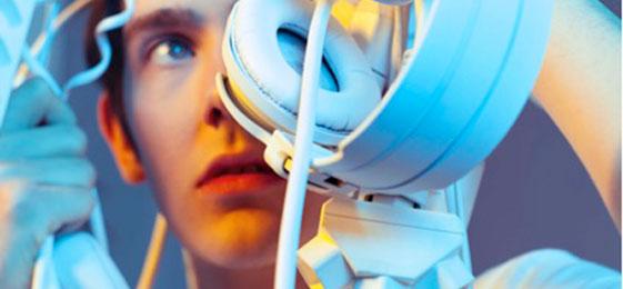 The photo shows a young man with a lot of electronic devices